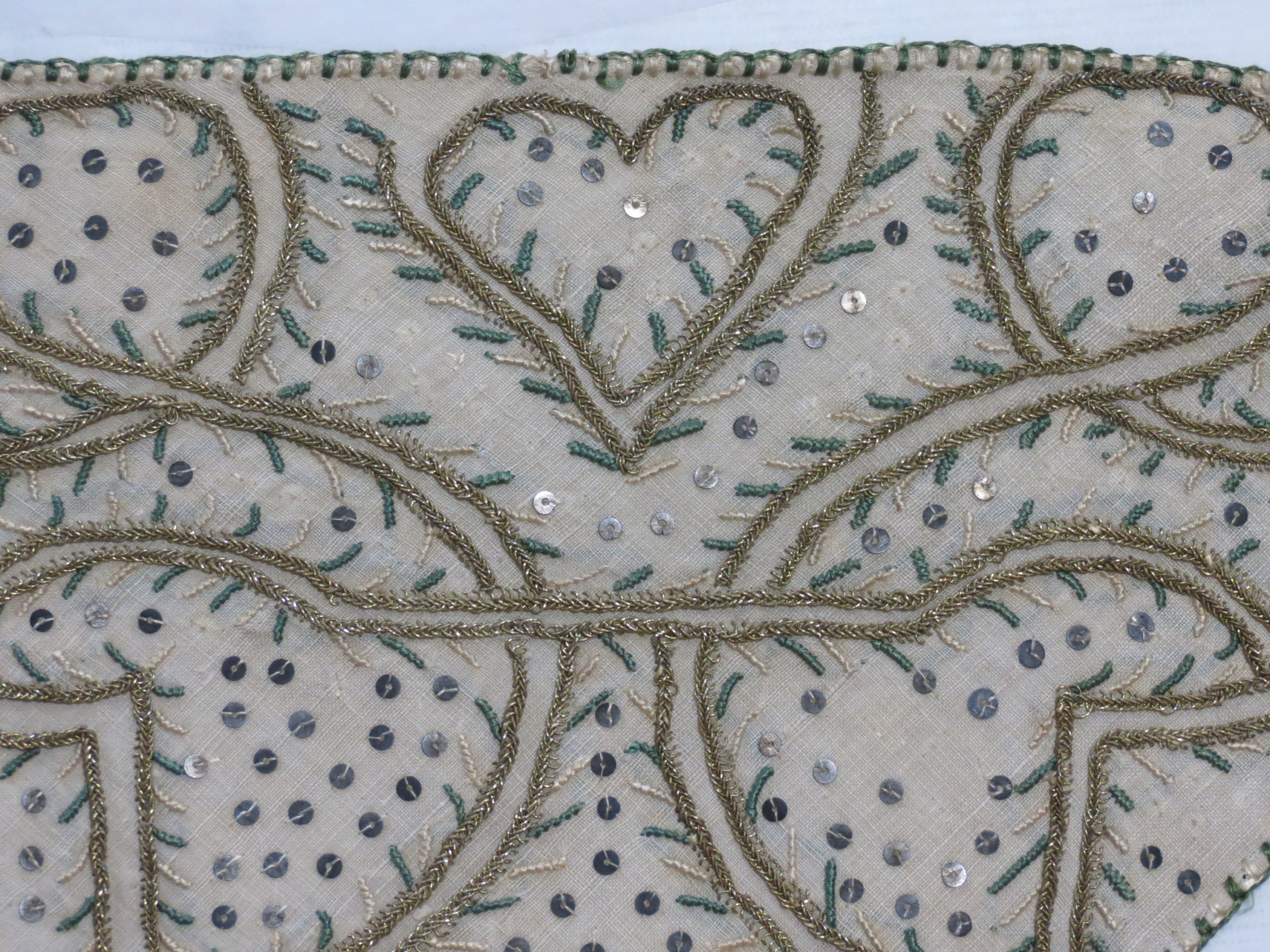 White linen forehead cloth embroidered with gold thread forming a heart, green and white silk embroidery, metal spangles.